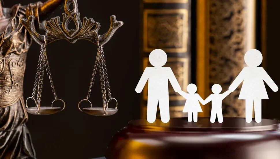 Balança da justiça ao lado de recorte de papel representando uma família