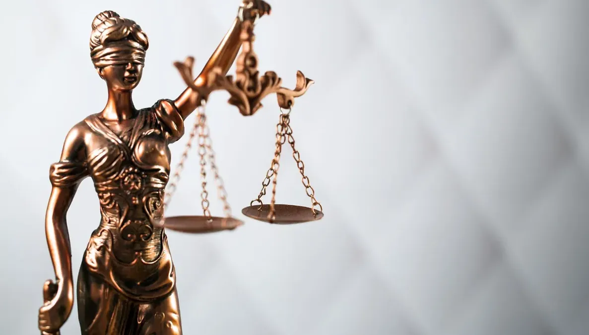 Estatueta da justiça com balança sobre fundo claro